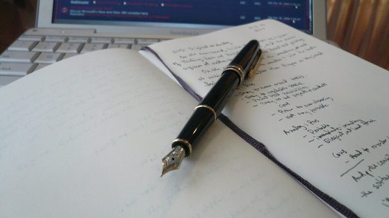 A notebook and pen open on a desk